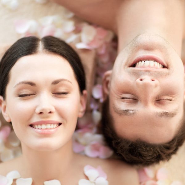 faces of couple in spa salon lying on the massage desks